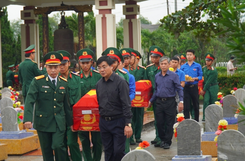 Các đồng chí lãnh đạo huyện di chuyển hài cốt đến vị trí an táng. Ảnh: Anh Vũ.